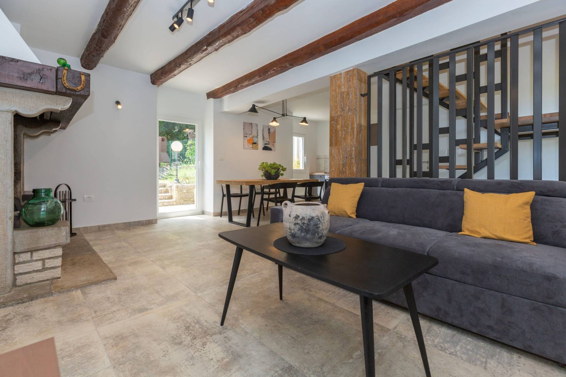 Living room with dining table and kitchen in the back and stairs to upper floor