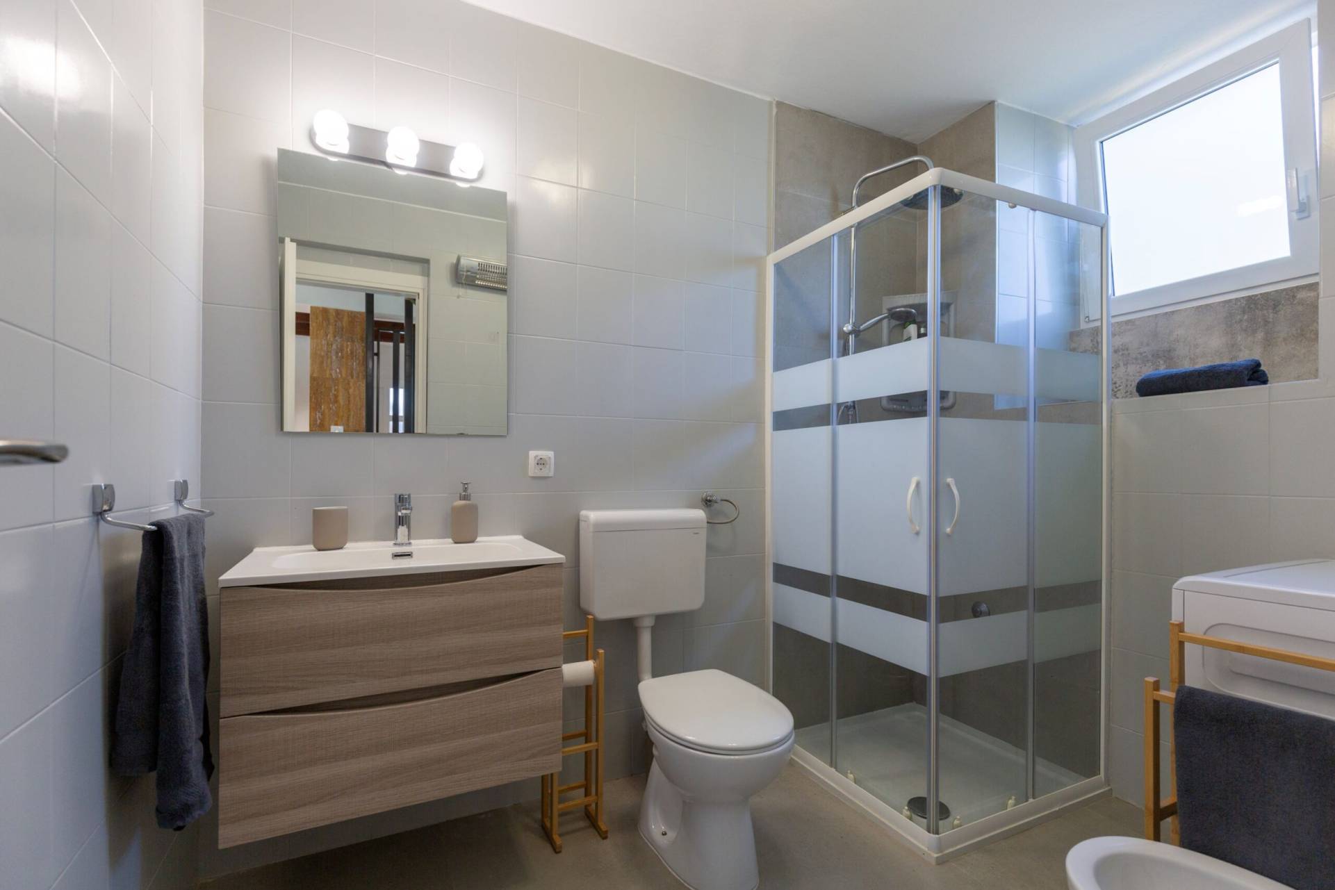 Modern bathroom with shower cabin, toilet, washing machine and sink