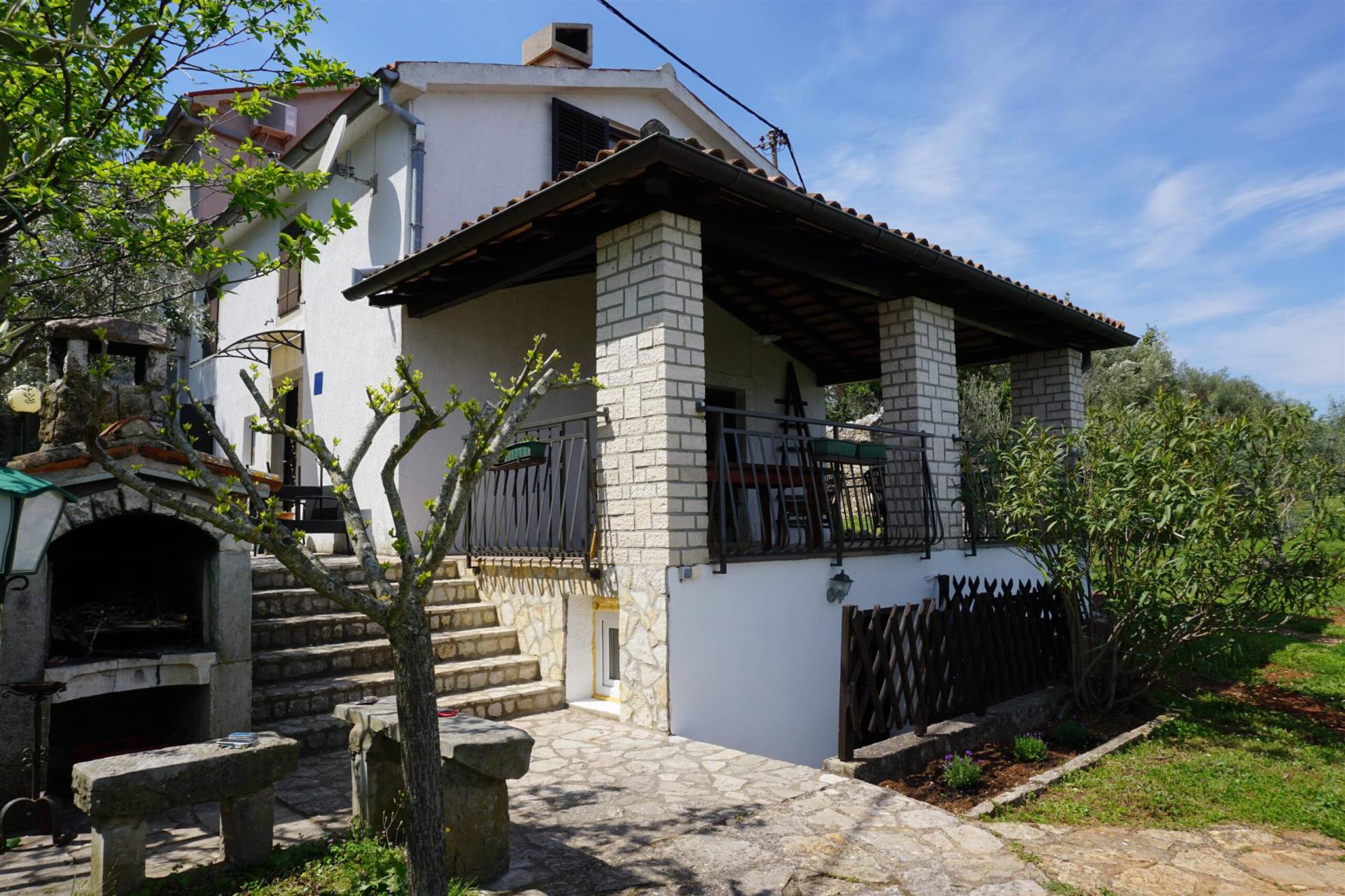 Front view of the house with entrance to the basement, terrace and fireplace for barbecue