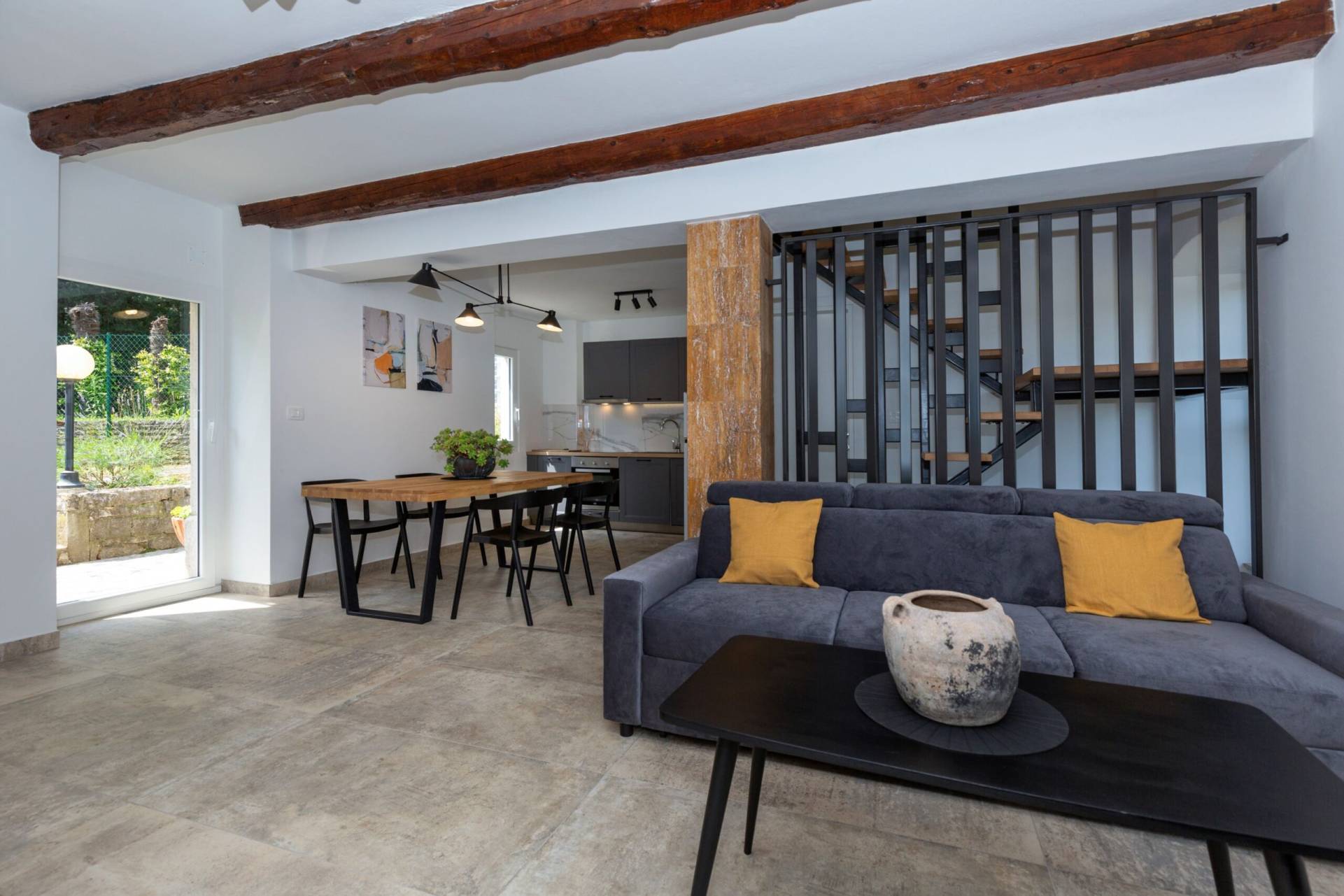 Living room with dining table and kitchen in the back and stairs to upper floor
